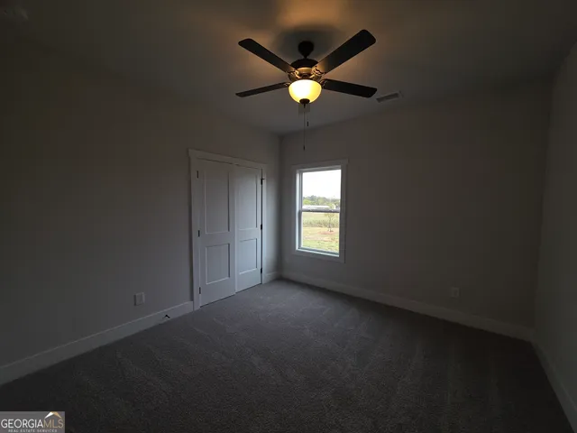 a view of an empty room with window and chandelier fan