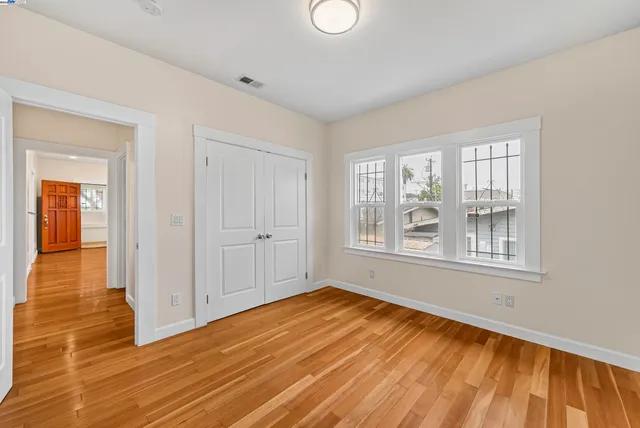 an empty room with wooden floor and windows