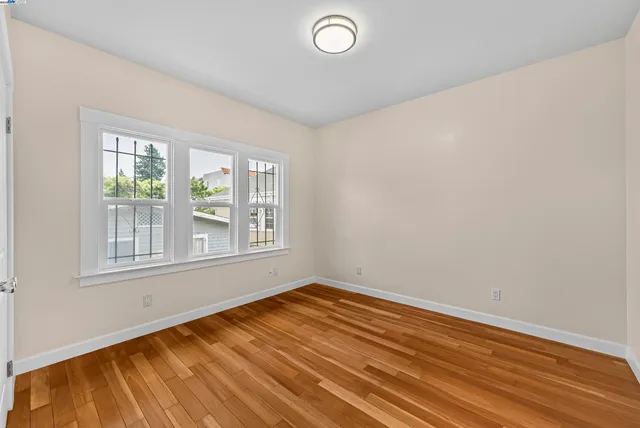 a view of an empty room with wooden floor and closet
