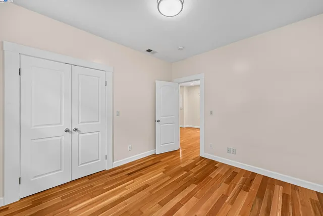 a view of an empty room with wooden floor and windows