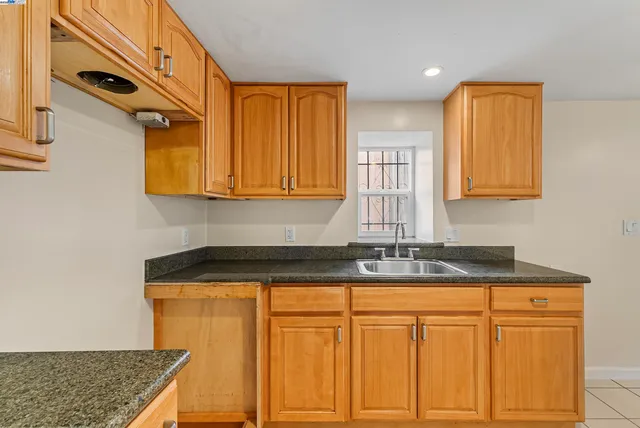 a kitchen with granite countertop cabinets stainless steel appliances a sink and a window