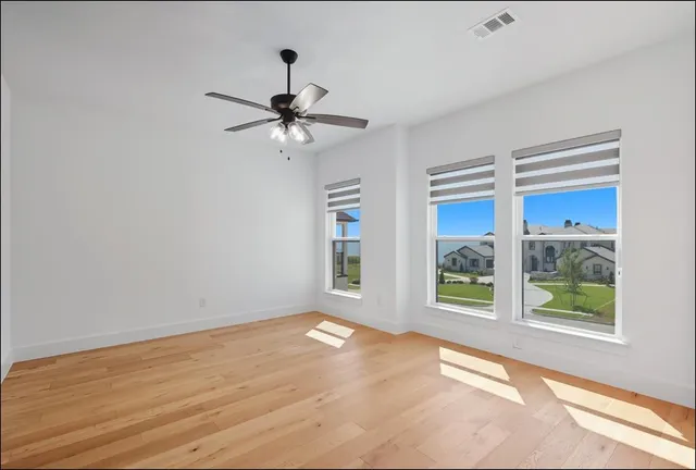 a view of empty room with wooden floor and fan