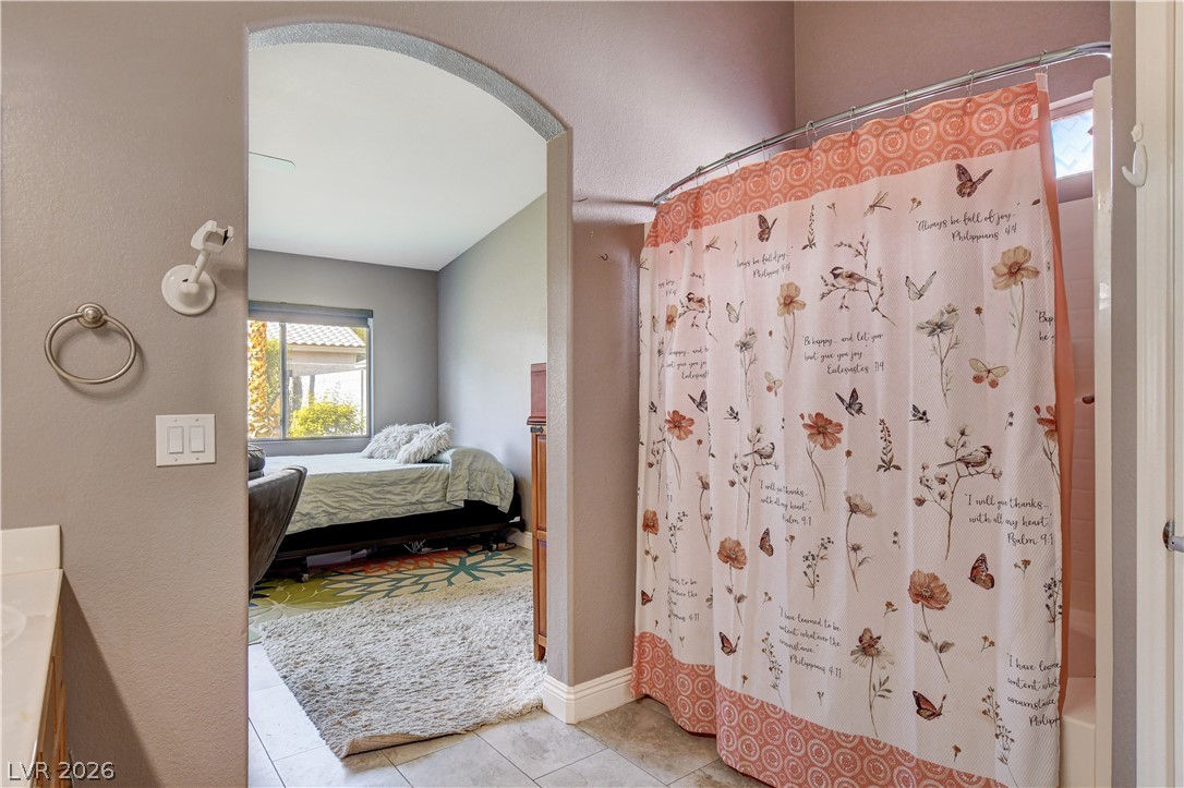 910 Cobblestone Cove Road North Las Vegas, NV 89081 - Photo 15 of 30 Step into a well-lit bedroom offering a peaceful retreat, separated by an elegant arched doorway from an adjacent space.