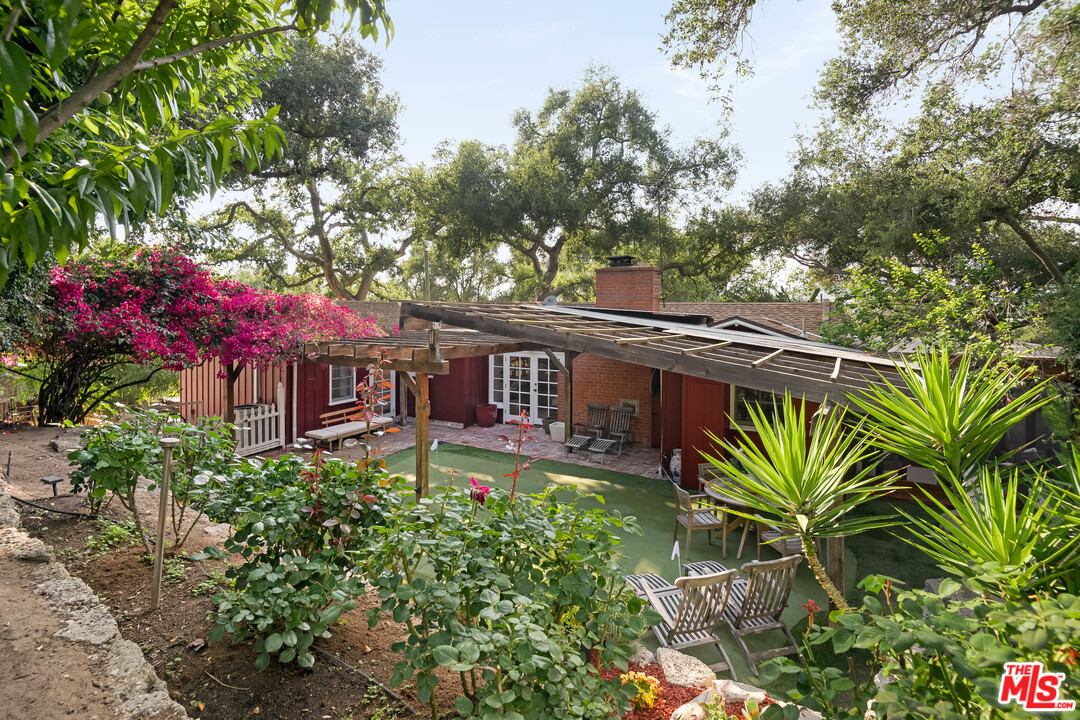 21042 Entrada Road Topanga, CA 90290 - Photo 37 of 49 a backyard of a house with table and chairs potted plants and large tree