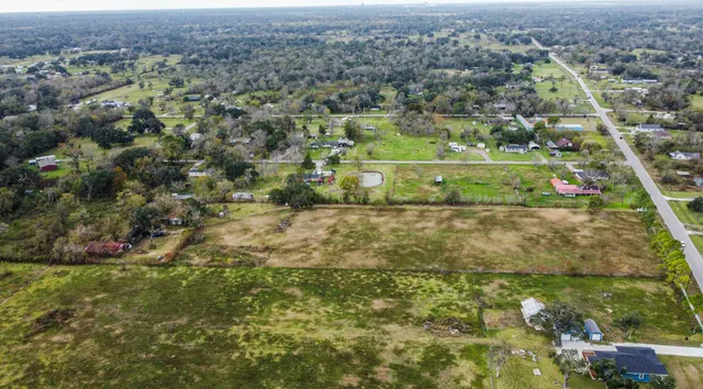 an aerial view of residential houses with outdoor space and trees