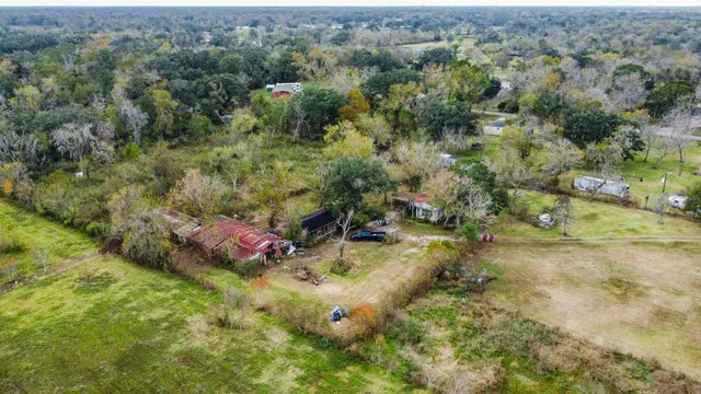 an aerial view of residential house with outdoor space and trees all around