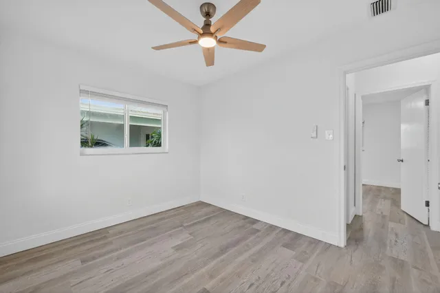 an empty room with wooden floor and a ceiling fan