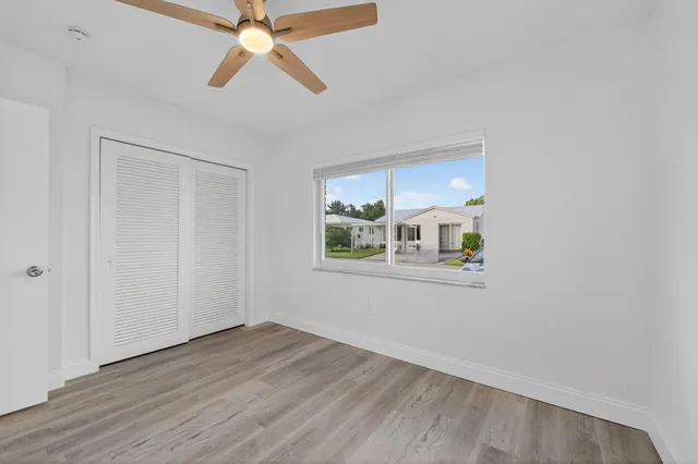 a view of an empty room with window and wooden floor