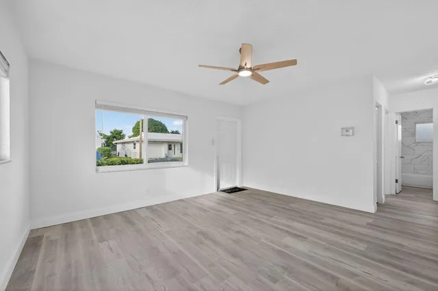 a view of empty room with wooden floor and ceiling fan