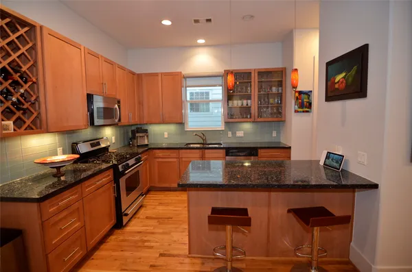 a kitchen with granite countertop a stove top oven a sink a counter space and cabinets