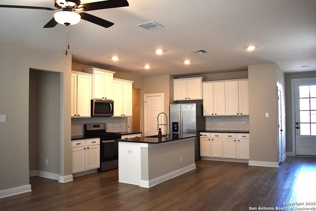 9210 Espadrille Run Converse, TX 78109 - Photo 5 of 17 a kitchen with stainless steel appliances kitchen island granite countertop a stove top oven a sink a refrigerator with wooden floor and cabinets