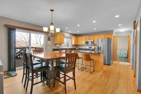 a dining room with stainless steel appliances granite countertop a dining table chairs and chandelier