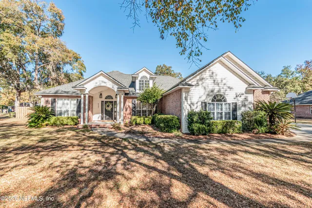 a view of a white house with a large windows and flower plants
