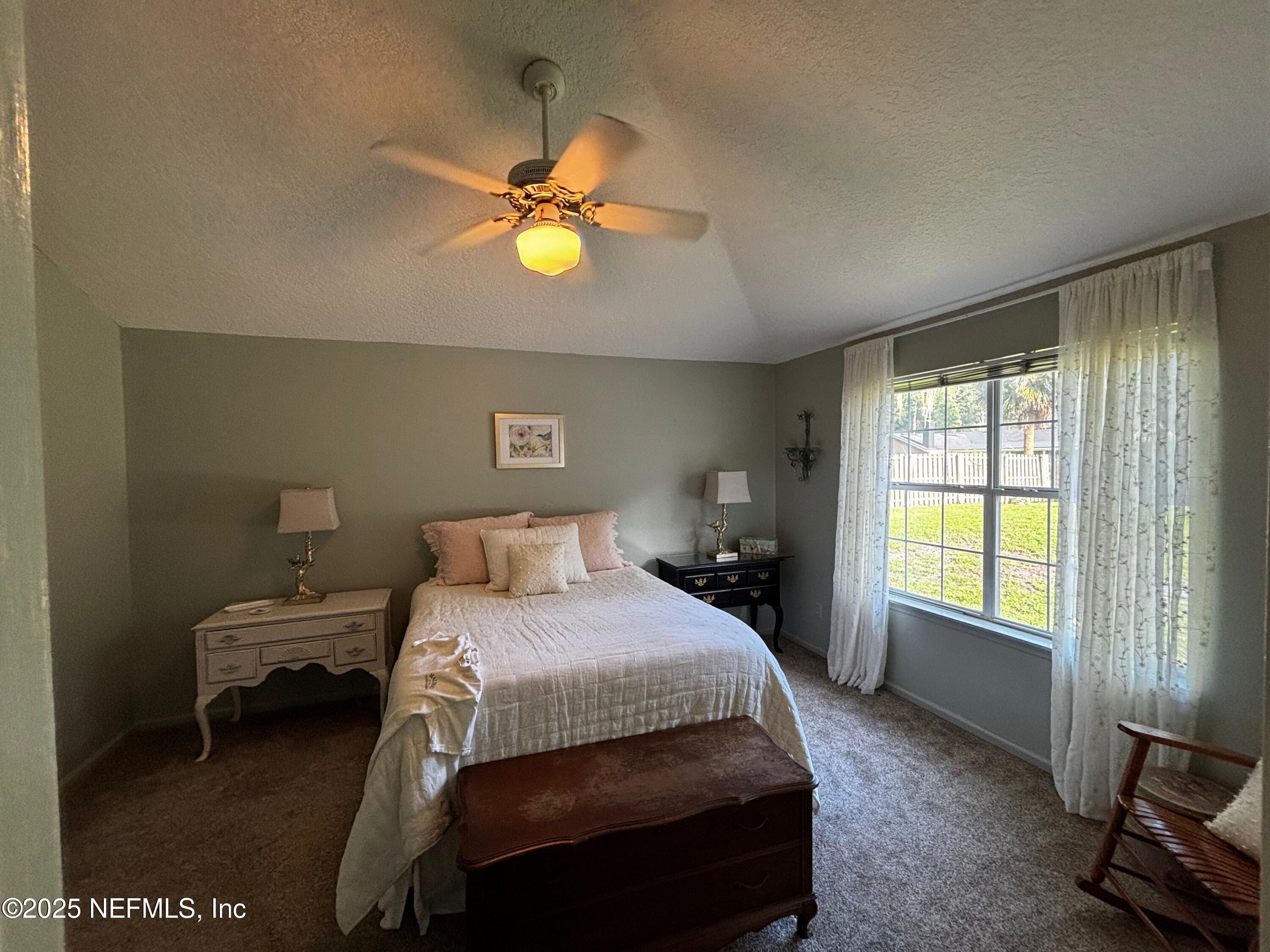 6121 Michele Road Macclenny, FL 32063 - Photo 15 of 26 a bedroom with a bed a chandelier and a window