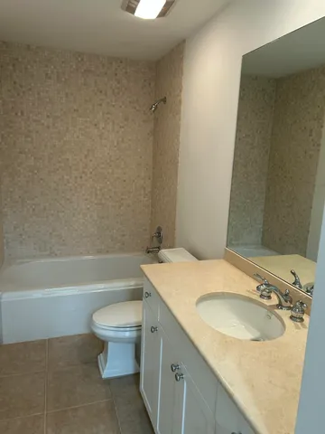 a bathroom with a granite countertop sink a toilet a mirror and bathtub