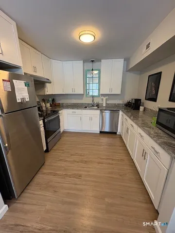 a large kitchen with stainless steel appliances granite countertop a stove a sink dishwasher and a refrigerator