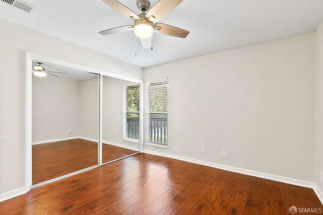 an empty room with wooden floor fan and windows