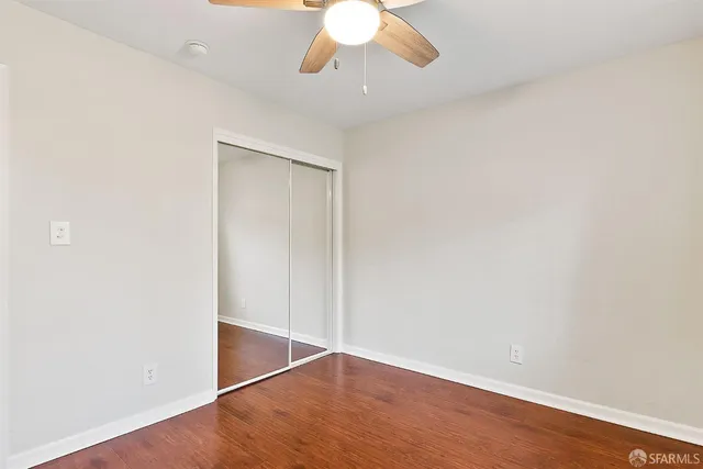 an empty room with wooden floor fan and window