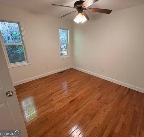 a view of an empty room with a window and wooden floor
