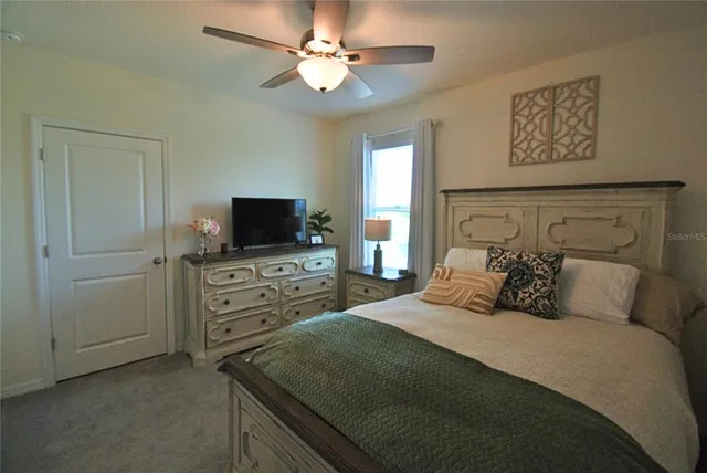 a bedroom with a bed and a flat tv screen on dresser