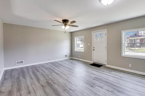 a view of an empty room with window and wooden floor