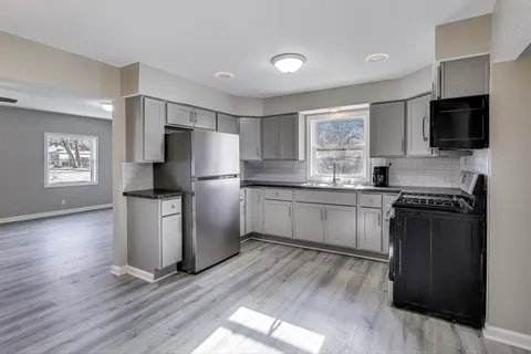 a kitchen with granite countertop a refrigerator stove top oven and sink