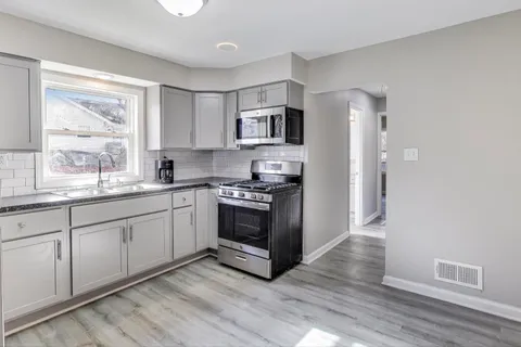 a kitchen with stainless steel appliances granite countertop a stove a sink and a refrigerator