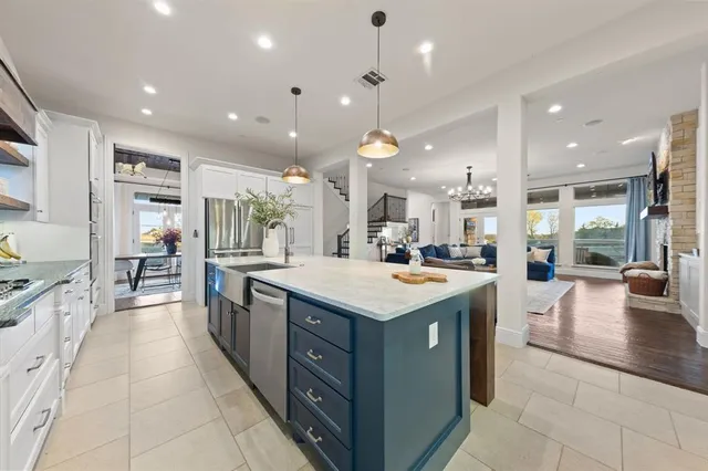 a kitchen with stainless steel appliances granite countertop a large kitchen island a stove a sink a oven and a dining table with the living room view