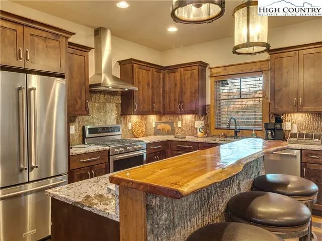 a kitchen with stainless steel appliances granite countertop a sink a stove and a refrigerator