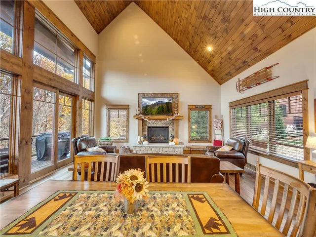 a living room with furniture large windows and wooden floor