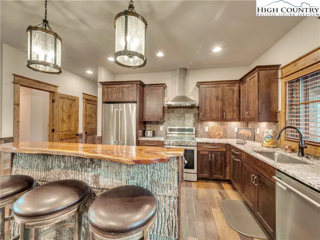 a kitchen with stainless steel appliances granite countertop a sink a stove a oven a dining table and chairs