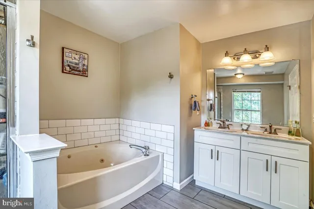 a bathroom with a tub a sink and mirror