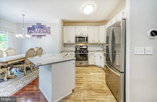 a kitchen with stainless steel appliances granite countertop a refrigerator and a stove top oven