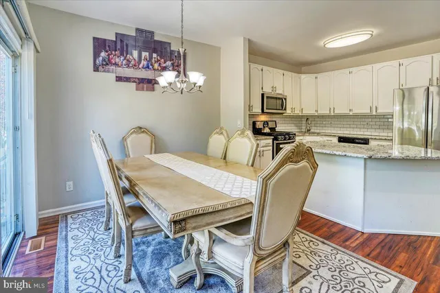a dining room with furniture a rug a chandelier and wooden floor