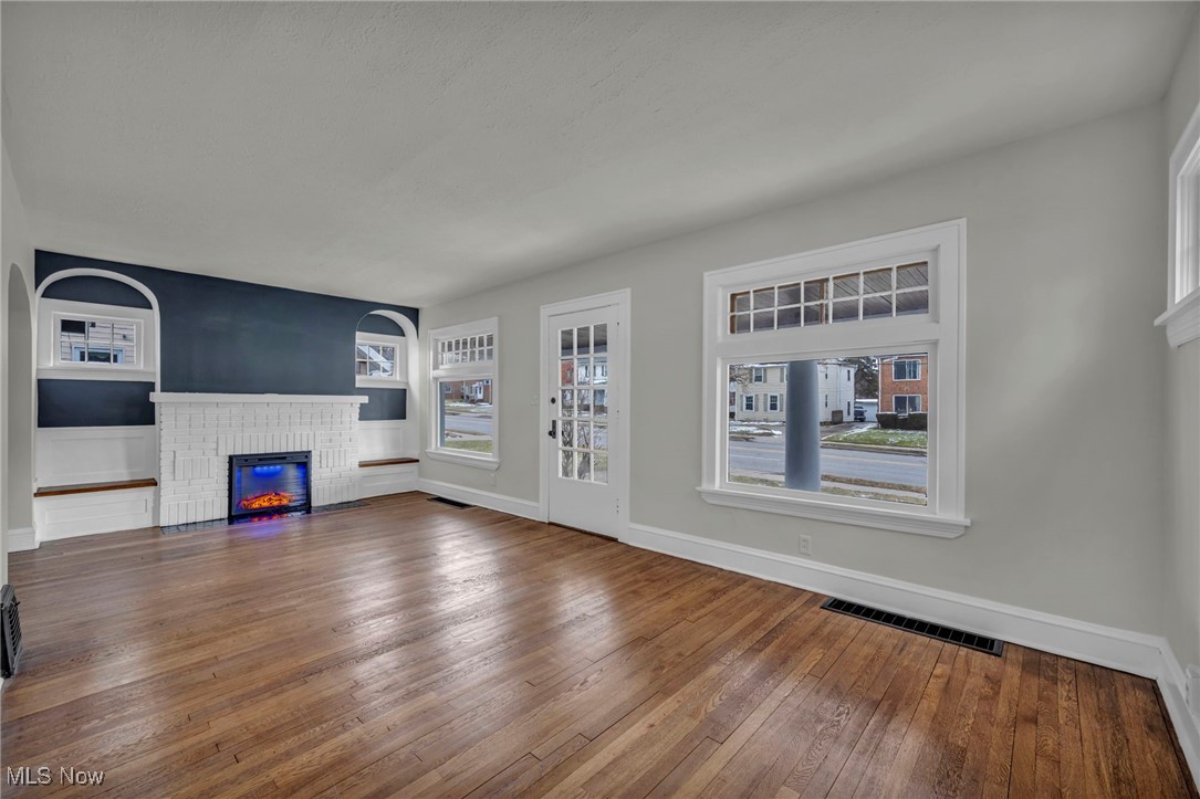 3577 Warren Road Cleveland, OH 44111 - Photo 5 of 17 Unfurnished living room featuring wood-type flooring, a fireplace, visible vents, and baseboards