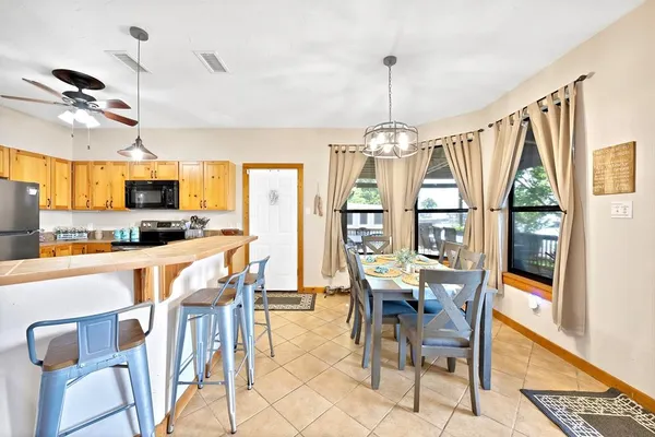 a dining room with stainless steel appliances kitchen island granite countertop a dining table chairs and granite counter tops