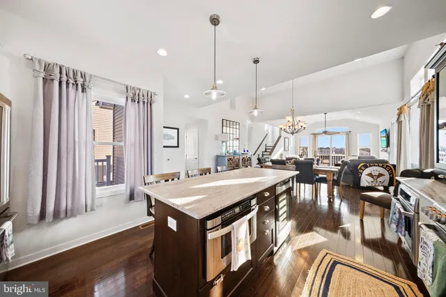 a kitchen with stainless steel appliances granite countertop a stove top oven a refrigerator a sink and a dining table with white cabinets