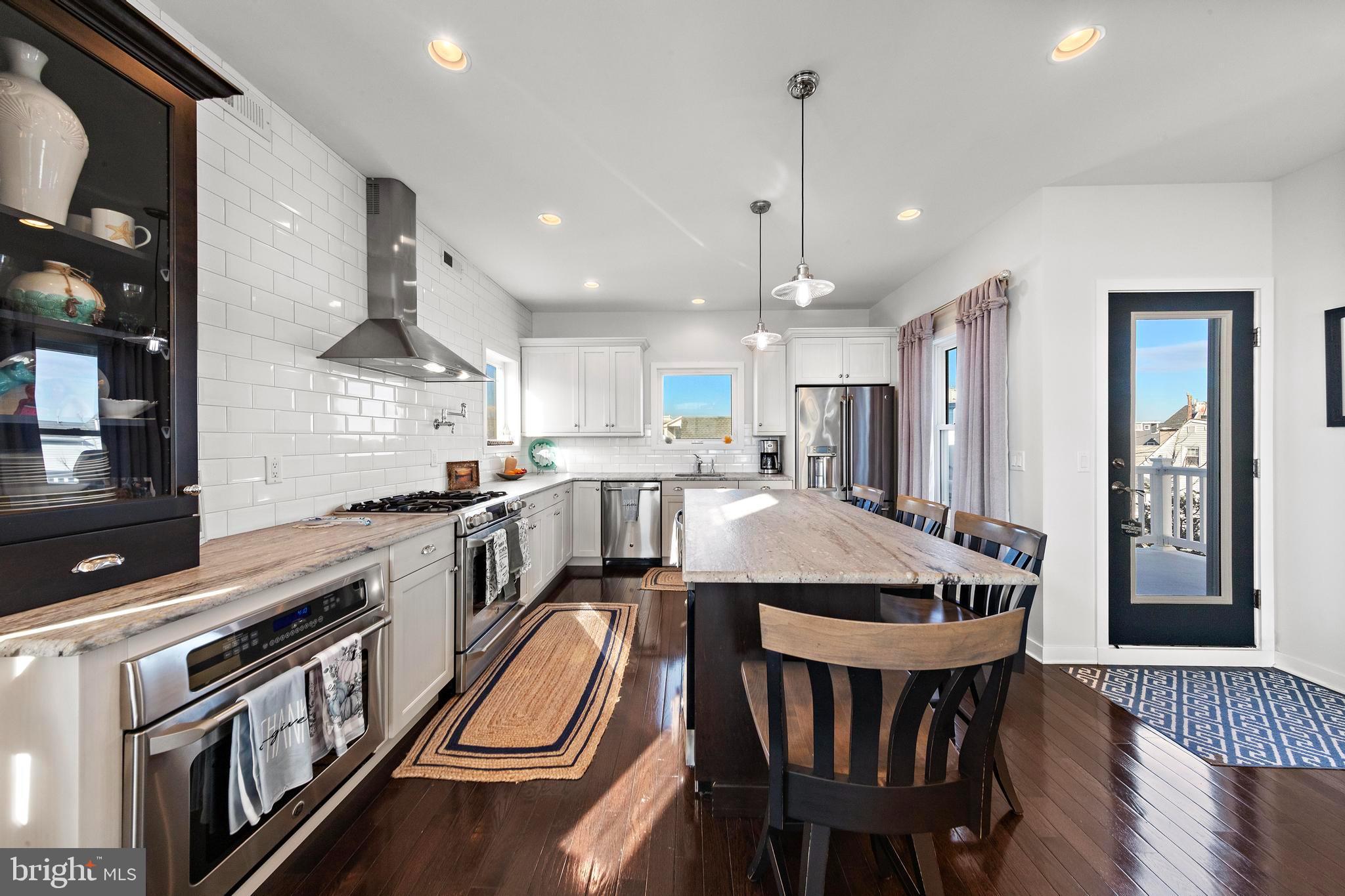 27 West 33rd Street Long Beach Township, NJ 08008 - Photo 44 of 83 a kitchen with stainless steel appliances granite countertop a stove top oven a refrigerator a sink and a dining table with white cabinets