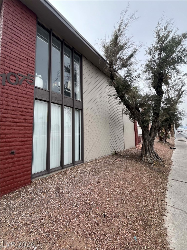 1075 East Desert Inn Road, Unit 5 Las Vegas, NV 89109 - Photo 12 of 12 A striking exterior combines brick and siding, featuring large windows and mature trees.