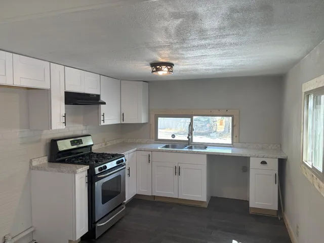 a kitchen with stainless steel appliances a sink dishwasher a stove and white cabinets