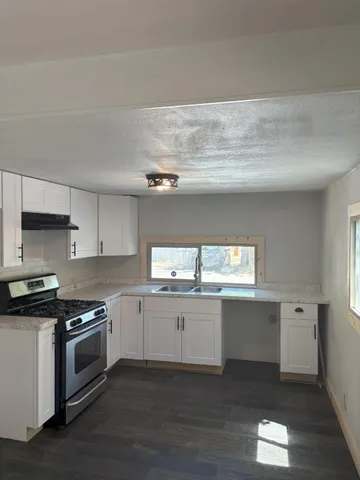 a kitchen with granite countertop white cabinets and white appliances