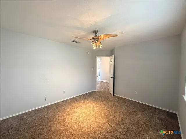 an empty room with a chandelier fan and windows