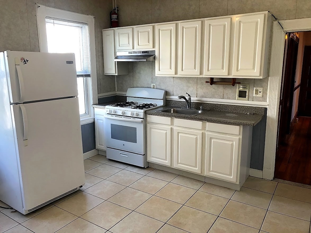 28 Litchfield Street, Unit 3 Boston, MA 02135 - Photo 7 of 11 a kitchen with white cabinets and white appliances