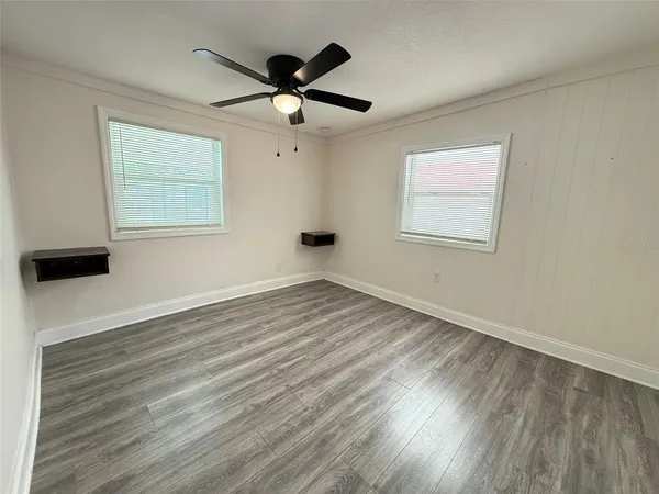 a view of empty room with wooden floor and fan