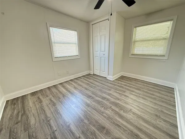 a view of an empty room with wooden floor and a window