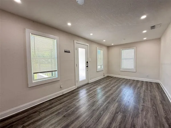 a view of an empty room with wooden floor and a window