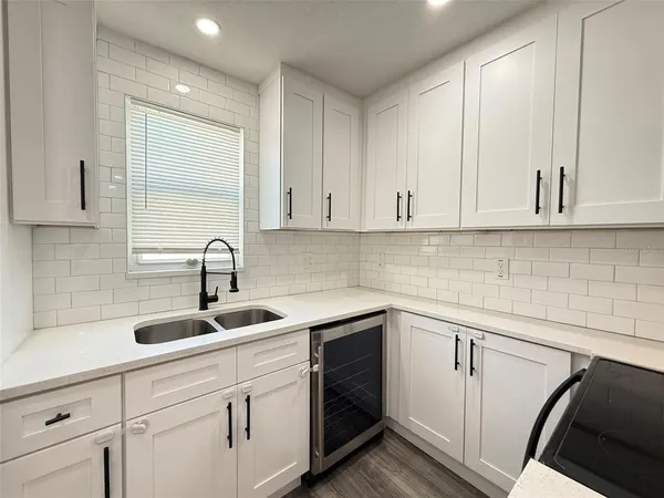 a kitchen with white cabinets sink and dishwasher