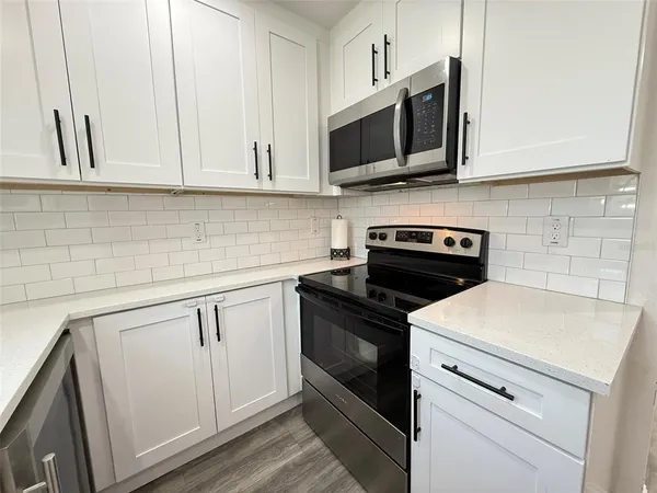 a kitchen with stainless steel appliances granite countertop white cabinets a microwave a sink and dishwasher