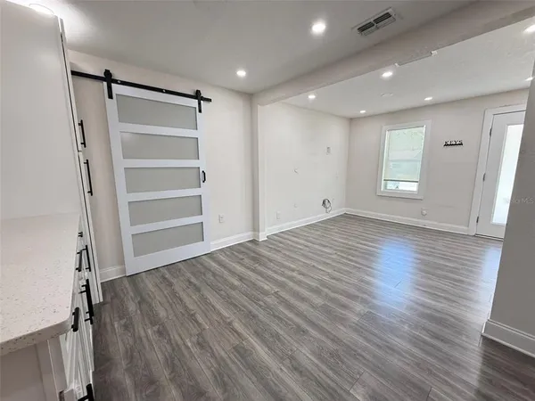 a view of empty room with wooden floor and window