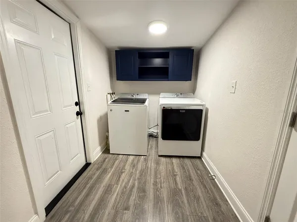 a utility room with wooden floor washer and dryer